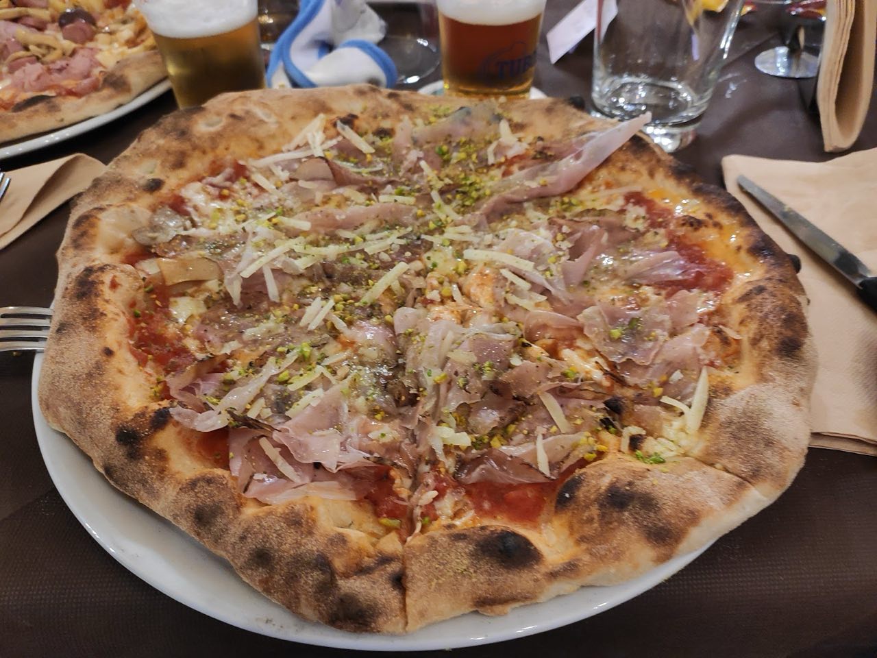 Pizza con prosciutto crudo, scaglie di grana e granella di pistacchio