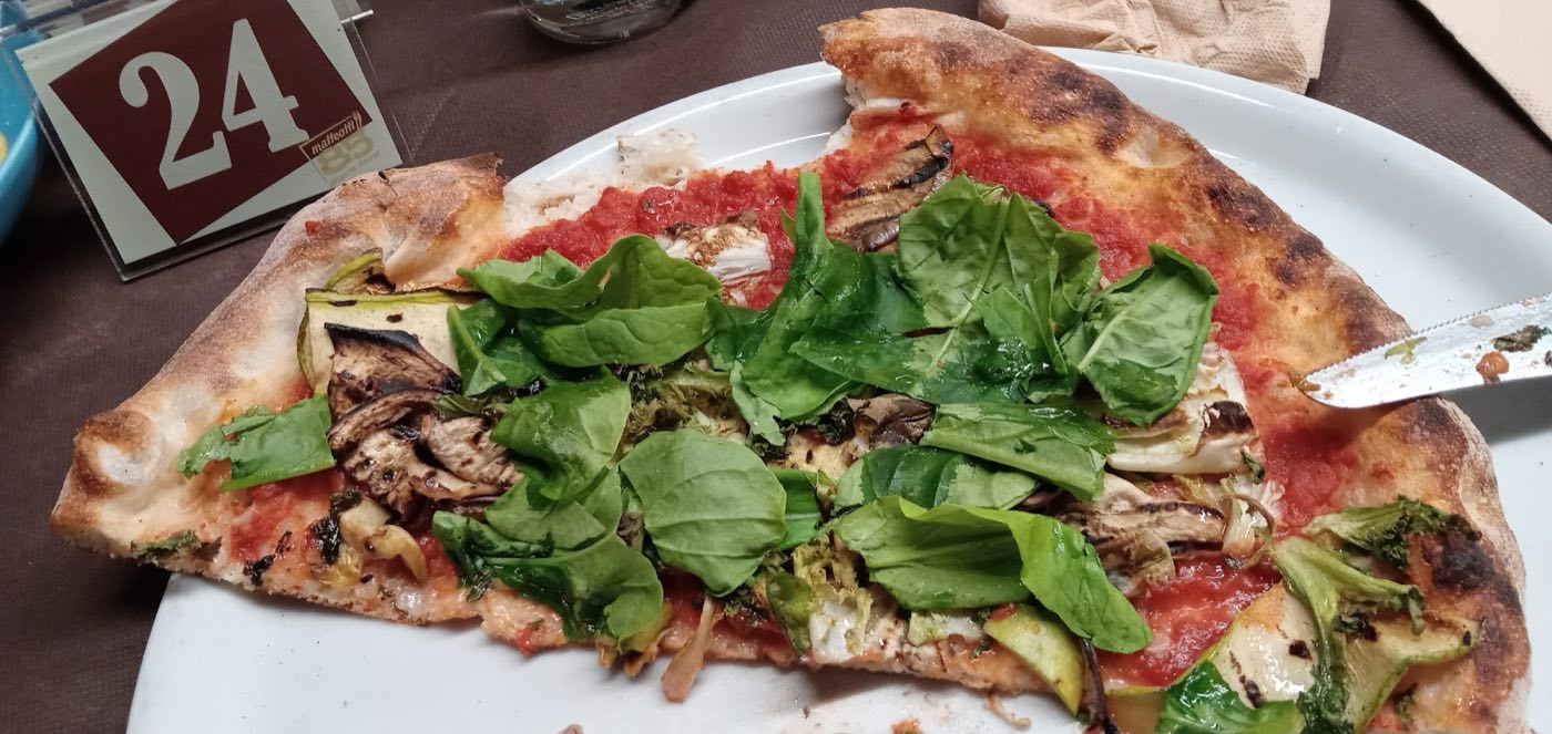 Pizza con verdure grigliate e rucola fresca, servita al tavolo